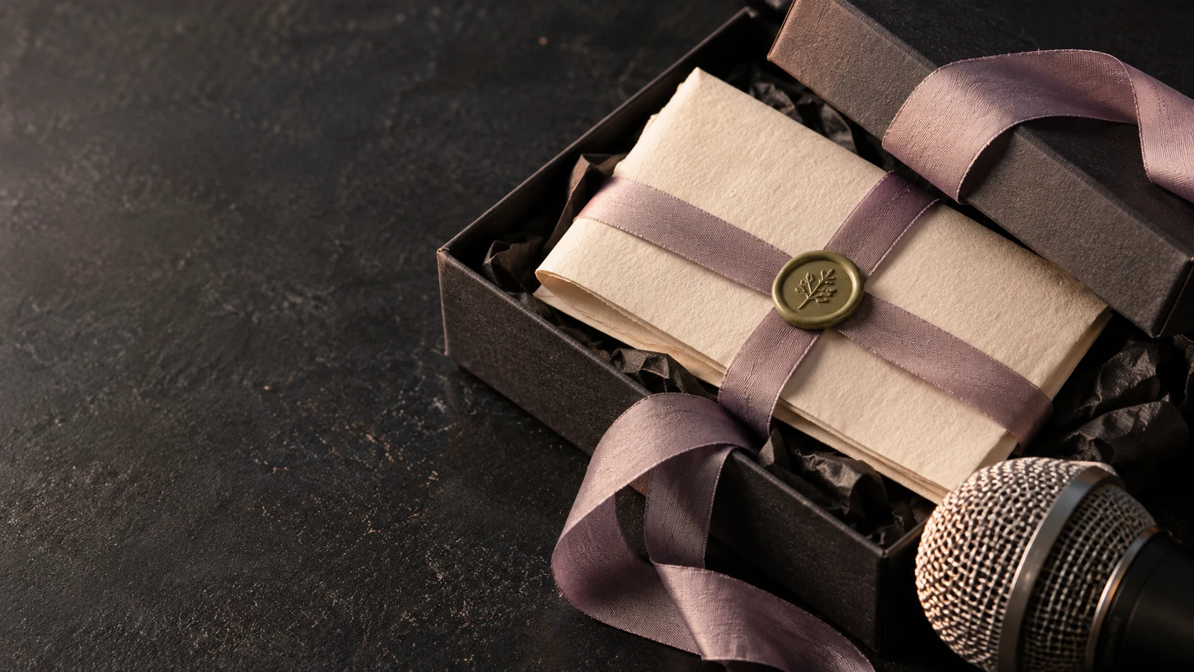 A silver microphone and folded lyric note inside a cream birthday gift box